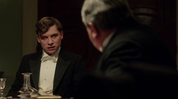 Movie still from “An Inspector Calls” (2015), directed by Raymond Pak-Ming Wong – A man in a tuxedo sitting next to another man in a suit; Close Up shot, Over the shoulder angle