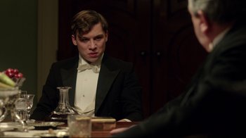 Movie still from “An Inspector Calls” (2015), directed by Raymond Pak-Ming Wong – A man in a tuxedo sitting in front of a table; Medium shot, Over the shoulder angle