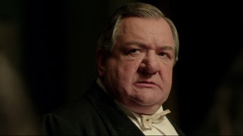 Movie still from “An Inspector Calls” (2015), directed by Raymond Pak-Ming Wong – An older man wearing a suit and bow tie; Close Up shot, Low angle