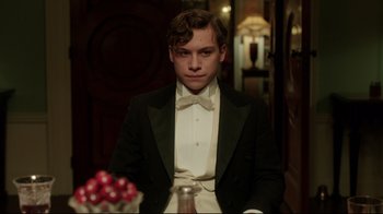 Movie still from “An Inspector Calls” (2015), directed by Raymond Pak-Ming Wong – A man in a tuxedo sitting in front of a table; Medium shot, Low angle