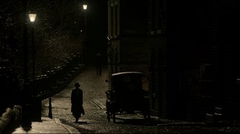 Movie still from “An Inspector Calls” (2015), directed by Raymond Pak-Ming Wong – A man walking down a street next to a carriage; Extreme Wide shot, High angle