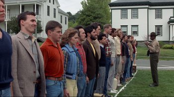 Movie still from “An Officer and a Gentleman” (1982), directed by Taylor Hackford – A group of people standing next to each other on a field; Wide shot, High angle