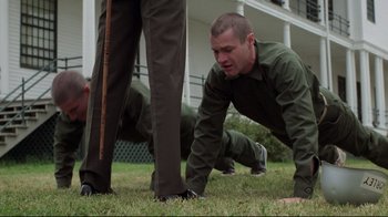 Movie still from “An Officer and a Gentleman” (1982), directed by Taylor Hackford – A man in a green shirt is crawling on the grass; Medium shot, Low angle