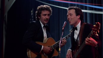 Movie still from “An Officer and a Gentleman” (1982), directed by Taylor Hackford – Two men in tuxedos are playing guitar and singing; Medium shot, Low angle