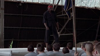 Movie still from “An Officer and a Gentleman” (1982), directed by Taylor Hackford – A man standing in front of a group of people; Wide shot, Low angle
