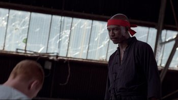 Movie still from “An Officer and a Gentleman” (1982), directed by Taylor Hackford – A man wearing a red bandanna standing next to a window; Medium shot, Low angle
