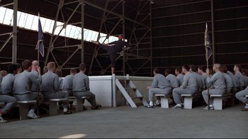 Movie still from “An Officer and a Gentleman” (1982), directed by Taylor Hackford – A man doing a skateboard trick in front of a group of people; Wide shot, Low angle
