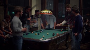 Movie still from “An Officer and a Gentleman” (1982), directed by Taylor Hackford – A group of people standing around a pool table; Wide shot, Over the shoulder angle