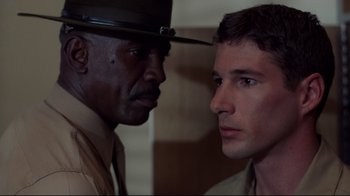 Movie still from “An Officer and a Gentleman” (1982), directed by Taylor Hackford – A man in a hat is looking at another man in a hat; Close Up shot, Over the shoulder angle