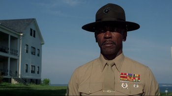 Movie still from “An Officer and a Gentleman” (1982), directed by Taylor Hackford – A man in a hat and uniform standing in front of a house; Medium shot, Low angle