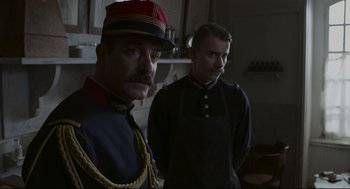 Movie still from “An Officer and a Spy” (2019), directed by Roman Polanski – Two men dressed in military uniforms standing next to each other in a kitchen; Medium shot, Low angle