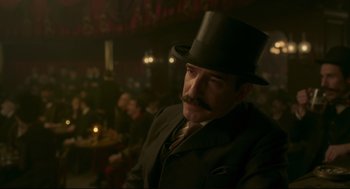 Movie still from “An Officer and a Spy” (2019), directed by Roman Polanski – A man in a suit and top hat in a room; Medium shot, Over the shoulder angle