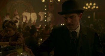 Movie still from “An Officer and a Spy” (2019), directed by Roman Polanski – A man in a suit and a hat in a room; Medium shot, Over the shoulder angle