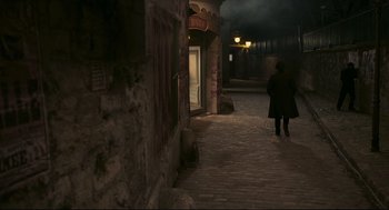 Movie still from “An Officer and a Spy” (2019), directed by Roman Polanski – A person walking down a street at night; Extreme Wide shot, High angle