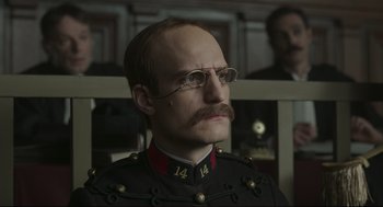 Movie still from “An Officer and a Spy” (2019), directed by Roman Polanski – A man with a mustache wearing glasses and a military uniform; Close Up shot, Low angle