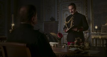 Movie still from “An Officer and a Spy” (2019), directed by Roman Polanski – A man in a military uniform standing in front of another man; Medium shot, Low angle