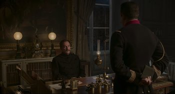 Movie still from “An Officer and a Spy” (2019), directed by Roman Polanski – A man in a uniform sitting in front of a table; Medium shot, Over the shoulder angle