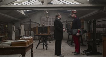 Movie still from “An Officer and a Spy” (2019), directed by Roman Polanski – Two men standing in a room talking to each other; Wide shot, Low angle