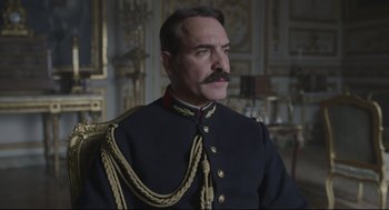 Movie still from “An Officer and a Spy” (2019), directed by Roman Polanski – A man in a military uniform sitting in a chair; Close Up shot, Low angle
