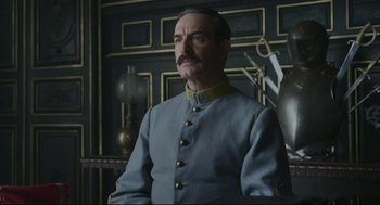 Movie still from “An Officer and a Spy” (2019), directed by Roman Polanski – A man in a uniform is standing in front of a wall; Medium shot, Low angle