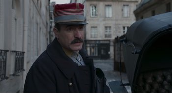 Movie still from “An Officer and a Spy” (2019), directed by Roman Polanski – An old man with a mustache wearing a hat; Medium shot, Low angle