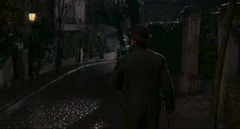 Movie still from “An Officer and a Spy” (2019), directed by Roman Polanski – A man walking down a street at night; Wide shot, High angle