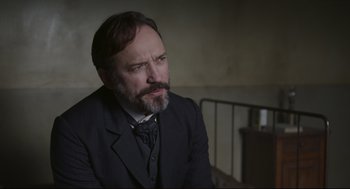 Movie still from “An Officer and a Spy” (2019), directed by Roman Polanski – A man in a suit and a tie looking to his left; Close Up shot, Over the shoulder angle