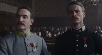 Movie still from “An Officer and a Spy” (2019), directed by Roman Polanski – Two men in military garb standing next to each other in front of an audience; Close Up shot, Low angle