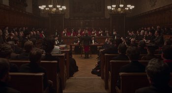 Movie still from “An Officer and a Spy” (2019), directed by Roman Polanski – A group of people sitting in a room with chairs; Extreme Wide shot, High angle