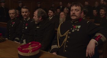 Movie still from “An Officer and a Spy” (2019), directed by Roman Polanski – A group of men sitting in front of each other in a courtroom; Medium shot, Over the shoulder angle
