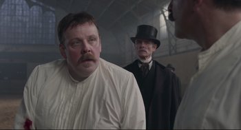 Movie still from “An Officer and a Spy” (2019), directed by Roman Polanski – A man with a beard and a mustache wearing a top hat; Medium shot, Low angle