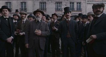 Movie still from “An Officer and a Spy” (2019), directed by Roman Polanski – A group of men standing next to each other in suits; Wide shot, Low angle