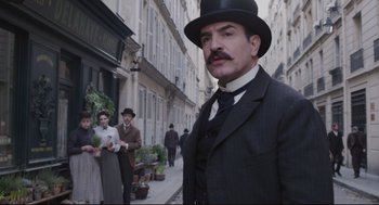 Movie still from “An Officer and a Spy” (2019), directed by Roman Polanski – A man with a mustache wearing a suit and a hat; Medium shot, Low angle