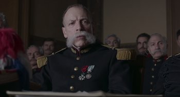 Movie still from “An Officer and a Spy” (2019), directed by Roman Polanski – An old man in a military uniform is sitting in front of a group of people; Close Up shot, Low angle