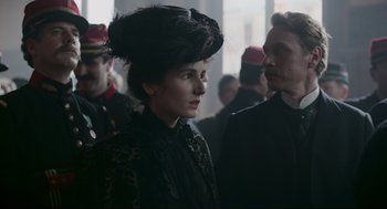 Movie still from “An Officer and a Spy” (2019), directed by Roman Polanski – A woman in a black dress and a man in a black suit; Close Up shot, Over the shoulder angle