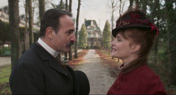 Movie still from “An Officer and a Spy” (2019), directed by Roman Polanski – A man and a woman standing next to each other in front of a house; Close Up shot, Low angle