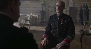 Movie still from “An Officer and a Spy” (2019), directed by Roman Polanski – A man in a military uniform sitting in a chair; Medium shot, Over the shoulder angle