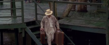 Movie still from “Anaconda” (1997), directed by Luis Llosa – An old man with two suitcases walking down a ramp; Wide shot, High angle