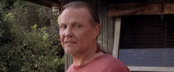 Movie still from “Anaconda” (1997), directed by Luis Llosa – An older man with long gray hair wearing a red shirt; Close Up shot, Low angle