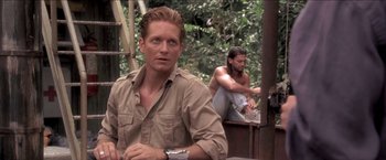 Movie still from “Anaconda” (1997), directed by Luis Llosa – A man sitting next to another man in a forest; Medium shot, Over the shoulder angle