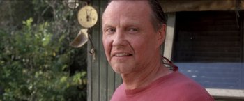 Movie still from “Anaconda” (1997), directed by Luis Llosa – An older man wearing a pink shirt with a clock in the background; Close Up shot, Low angle