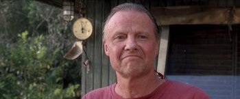 Movie still from “Anaconda” (1997), directed by Luis Llosa – An older man wearing a red t - shirt with a clock in the background; Close Up shot, Low angle