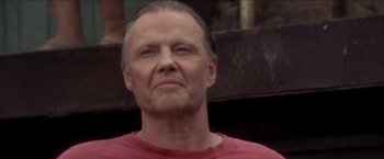 Movie still from “Anaconda” (1997), directed by Luis Llosa – An older man in a red shirt looking at the camera; Close Up shot, Low angle