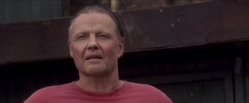 Movie still from “Anaconda” (1997), directed by Luis Llosa – An older man in a red shirt is looking at the camera; Close Up shot, Low angle