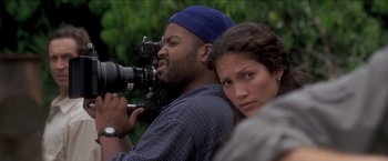 Movie still from “Anaconda” (1997), directed by Luis Llosa – A man and a woman with a video camera in front of trees; Close Up shot, Over the shoulder angle