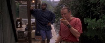 Movie still from “Anaconda” (1997), directed by Luis Llosa – Two men are standing on a dock and one is eating a hot dog; Medium shot, Low angle