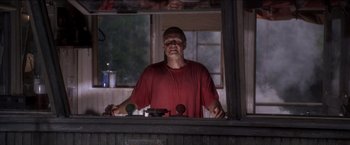 Movie still from “Anaconda” (1997), directed by Luis Llosa – A man standing in front of two microphones in front of a window; Medium shot, Low angle