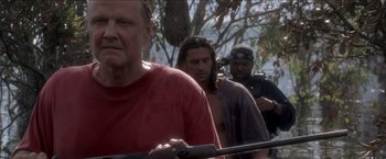 Movie still from “Anaconda” (1997), directed by Luis Llosa – A group of men standing next to each other holding guns; Medium shot, Over the shoulder angle