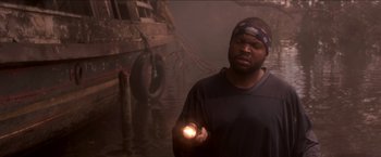 Movie still from “Anaconda” (1997), directed by Luis Llosa – A man holding a flashlight in front of an old boat; Medium shot, High angle
