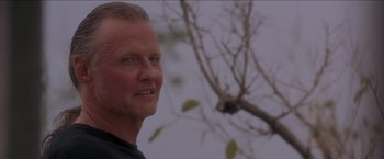Movie still from “Anaconda” (1997), directed by Luis Llosa – A man standing in front of a bare tree; Close Up shot, Low angle